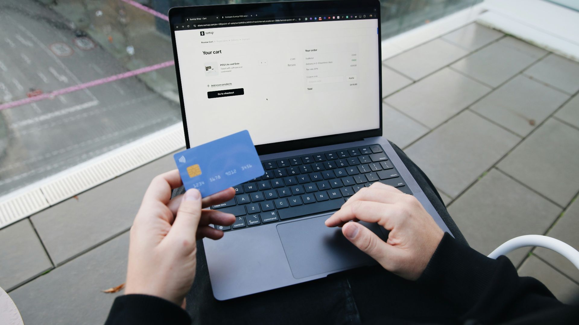 A person sitting in a chair with a laptop and a credit card