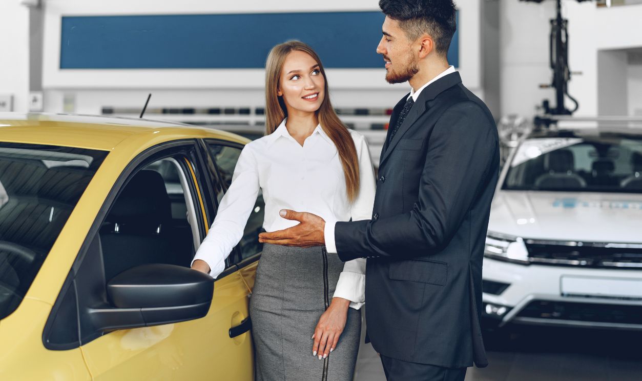 Man car dealer showing a woman buyer a new car