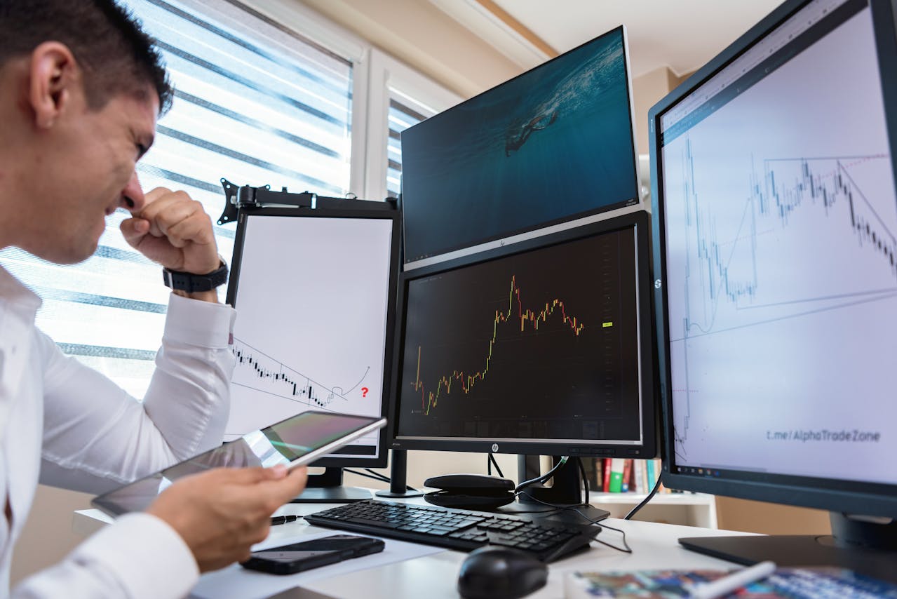 A man is Looking at the Line Graph on the Monitors (Stock)