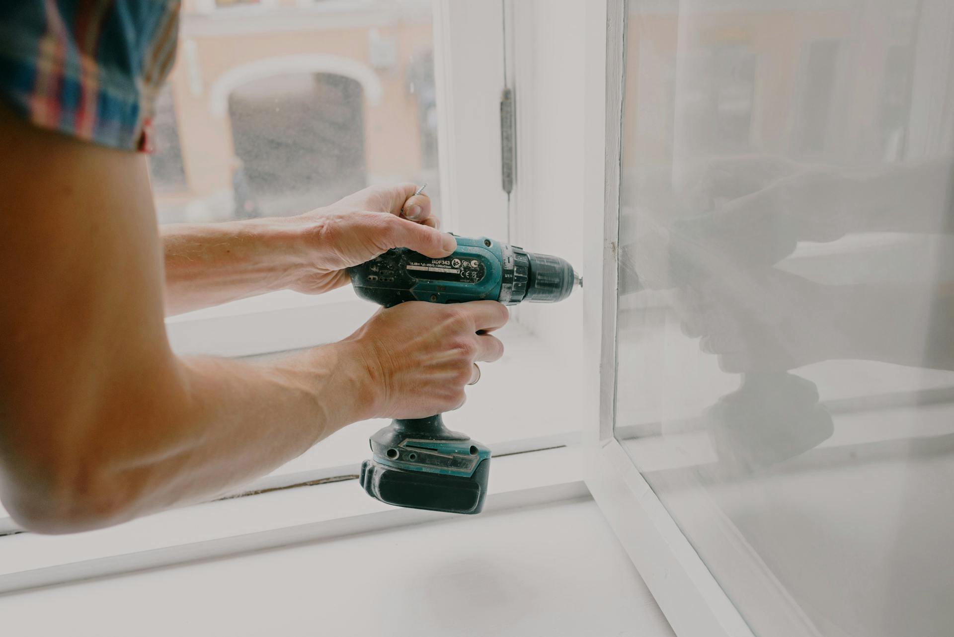 Workman screwing window frame during housework