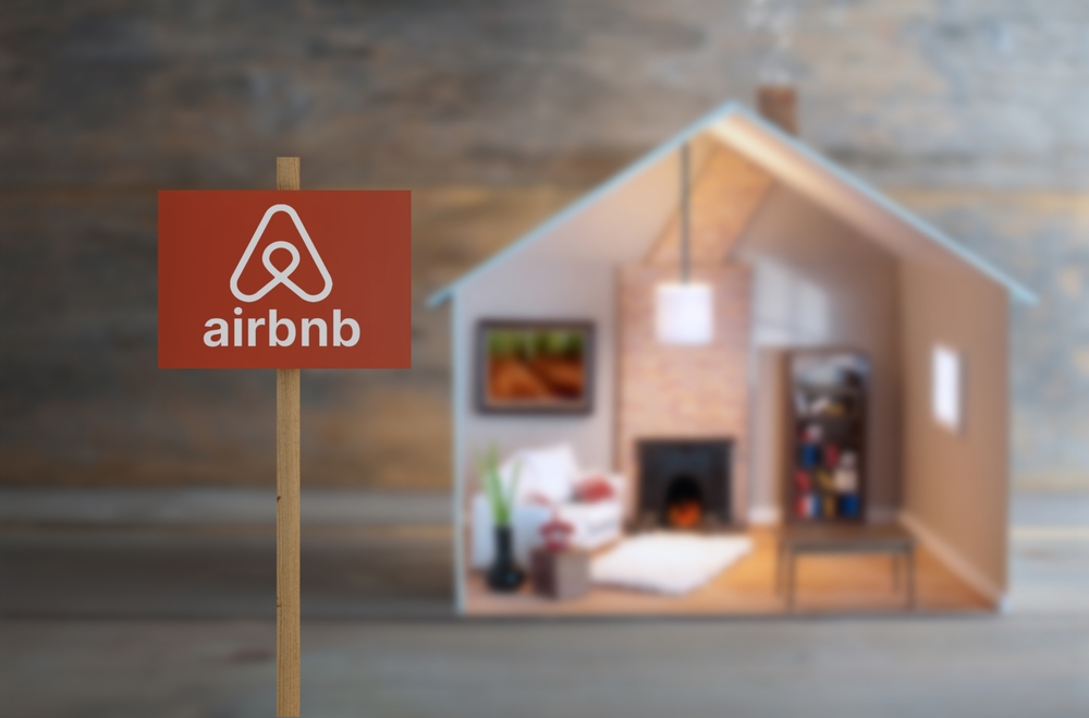 Airbnb sign next to a model house with lights on inside