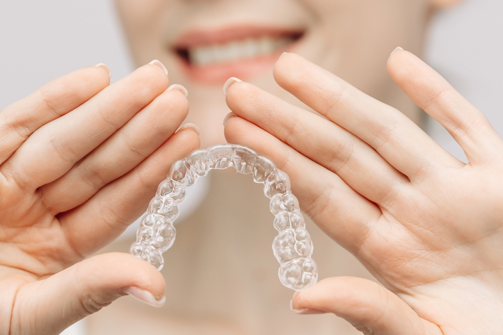 A woman with a beautiful smile and healthy teeth wears an orthodontic silicone trainer