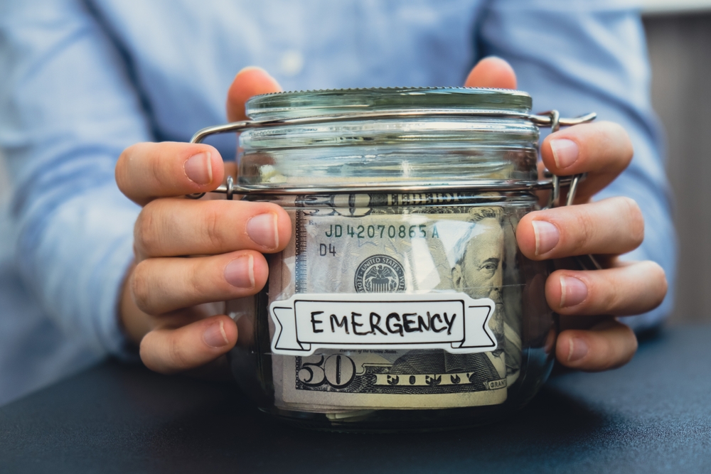 Female holding  Glass Jar with  EMERGENCY transcription on the jar filled with money