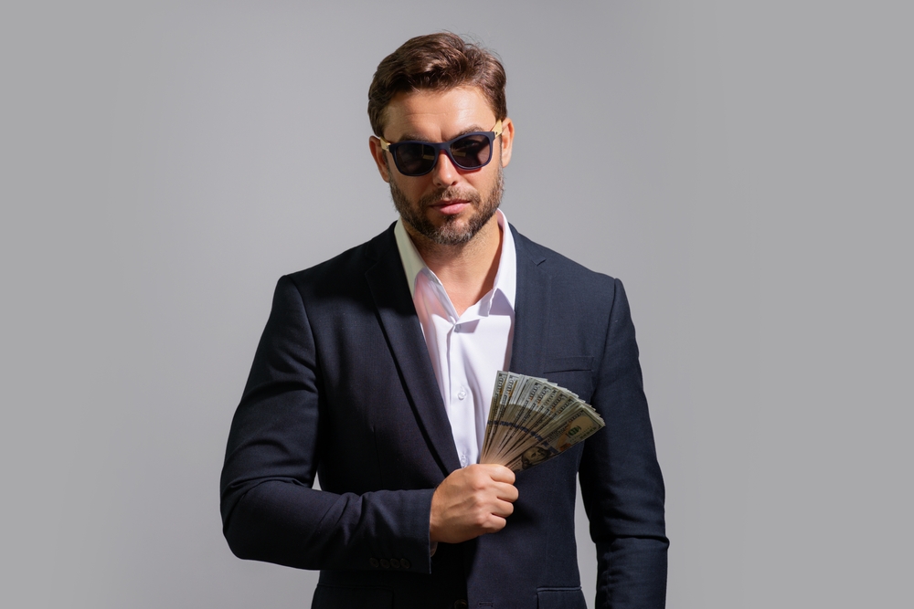 Man in suit and sunglasses  holding dollars banknotes