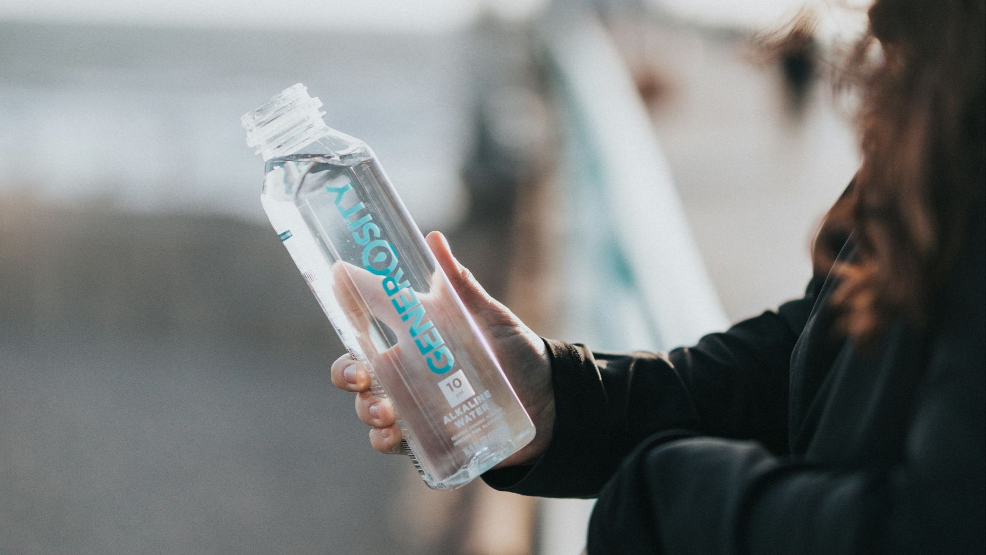 woman in black long sleeve shirt holding white plastic bottle