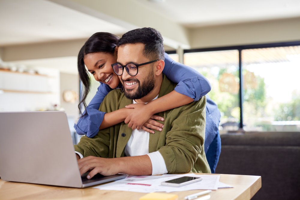 Couple embracing while using laptop at home