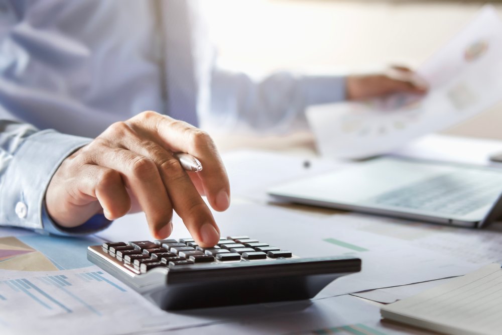 Photo of Accountant working on desk using calculator