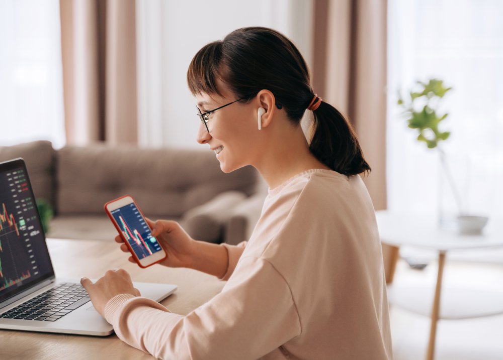 Smiling business woman trader analyst looking at laptop monitor