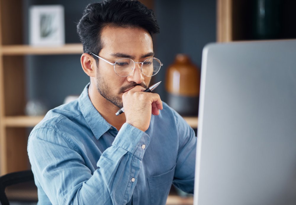 Serious, business man and thinking on computer in office