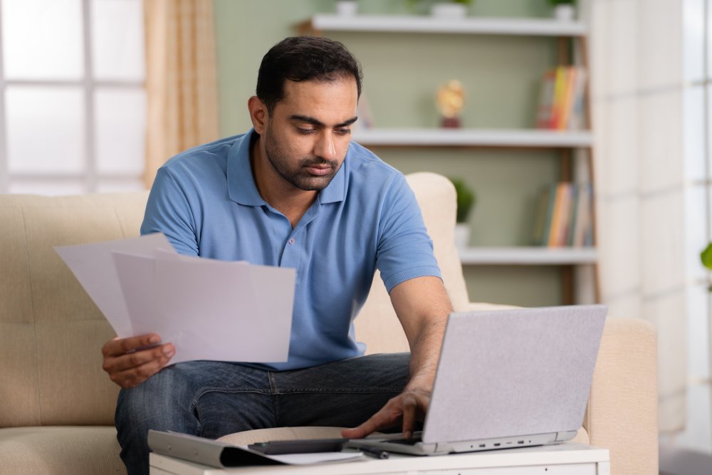 Man checking financial documents or insurance bills on laptop at hom