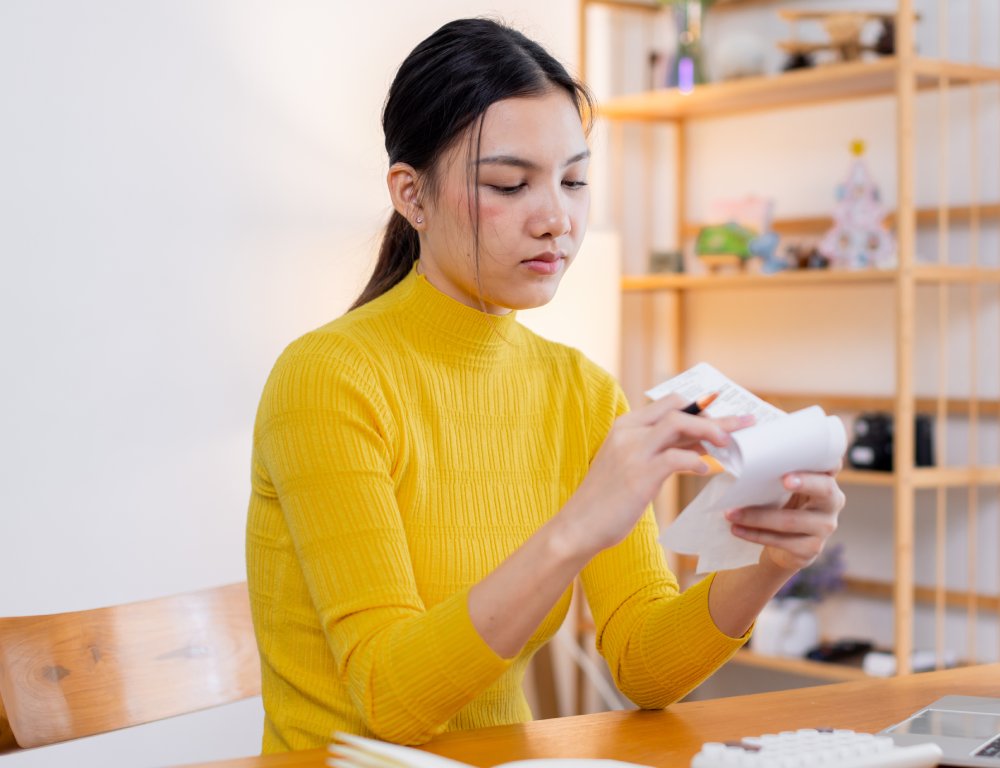 Stressed young asian woman calculating monthly home expenses