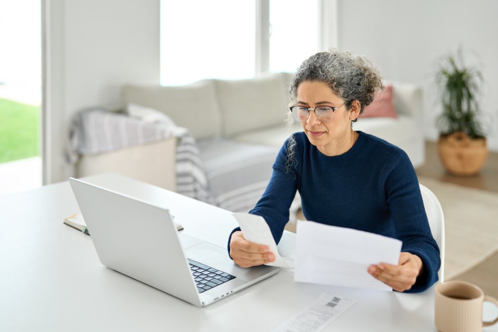 Mature lady paying bills online checking medical invoices receipts bills