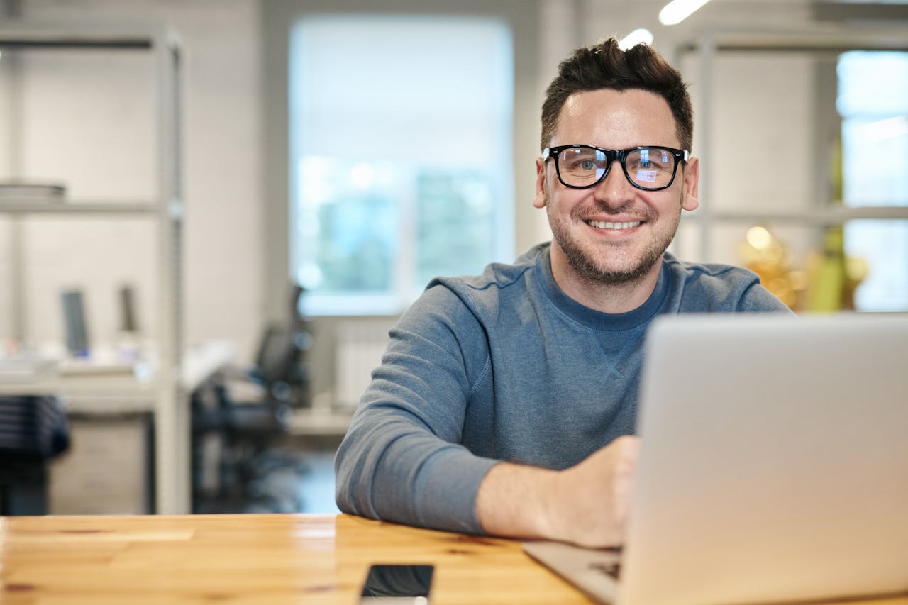 Photo of Man Wearing Eyeglasses in front of a laptop.