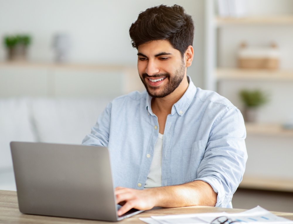 Positive freelancer working on laptop at home office