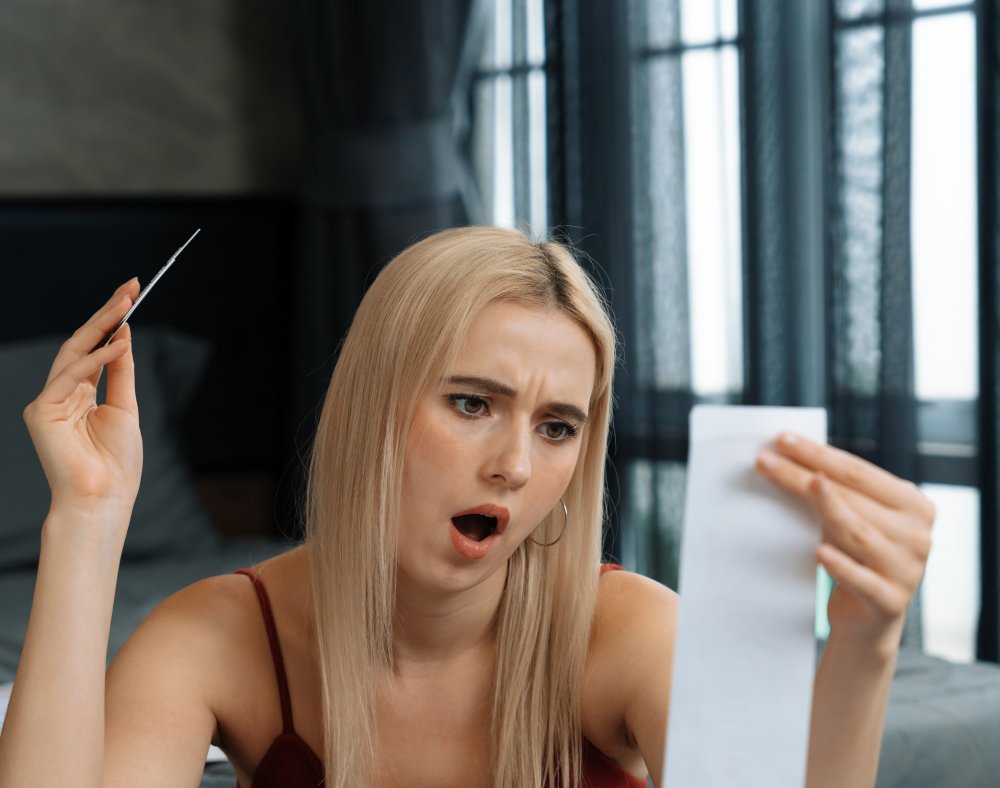 Stress worried young woman sit at table, as she pay bills online