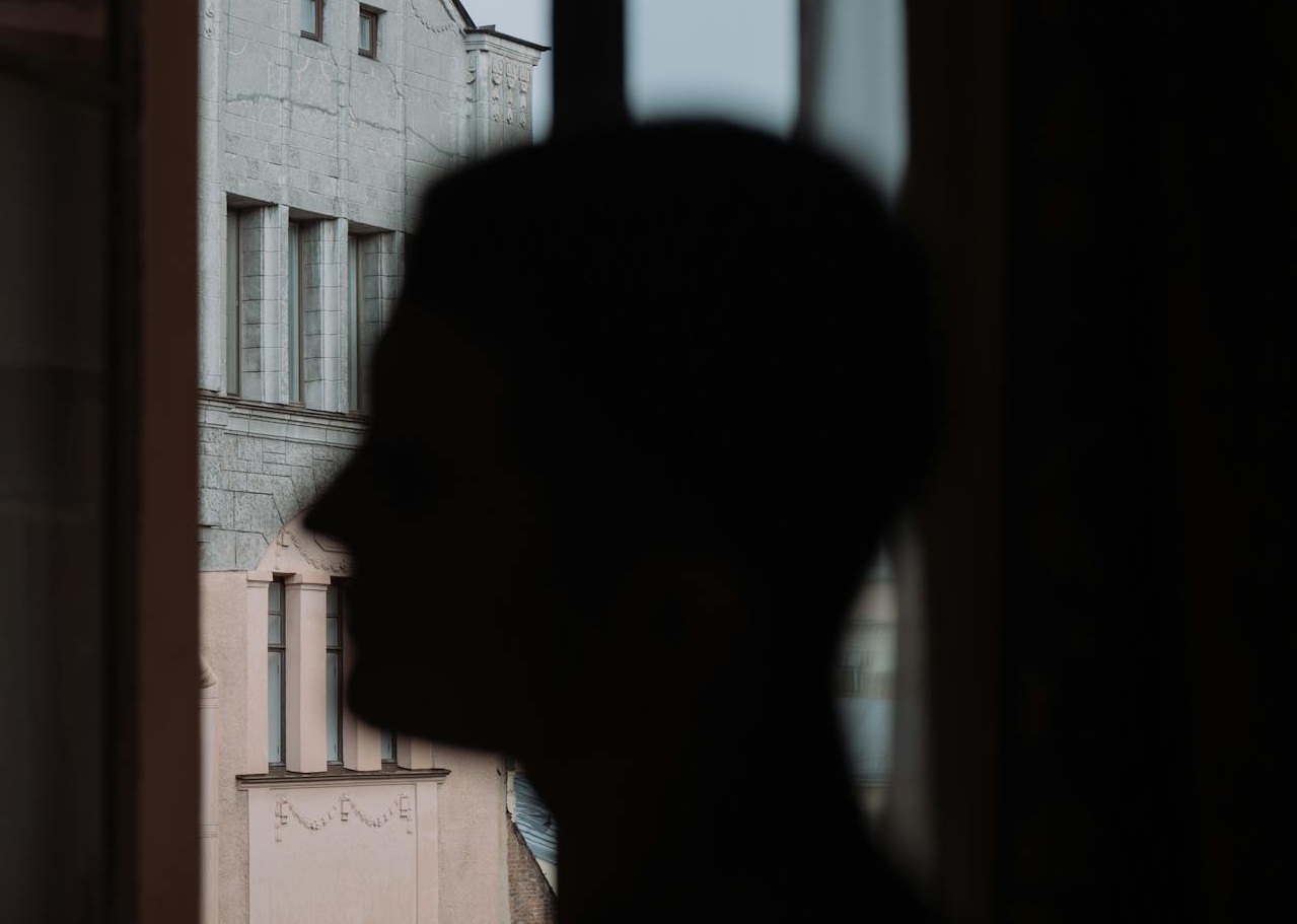 Person in White Shirt Standing Near Window