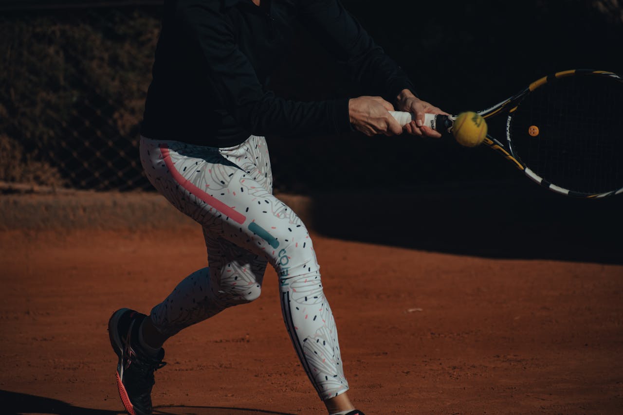 A Person in Black Jacket and White Leggings Playing Tennis