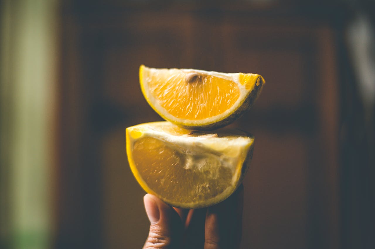 Photo Of Person Holding Sliced Lemon