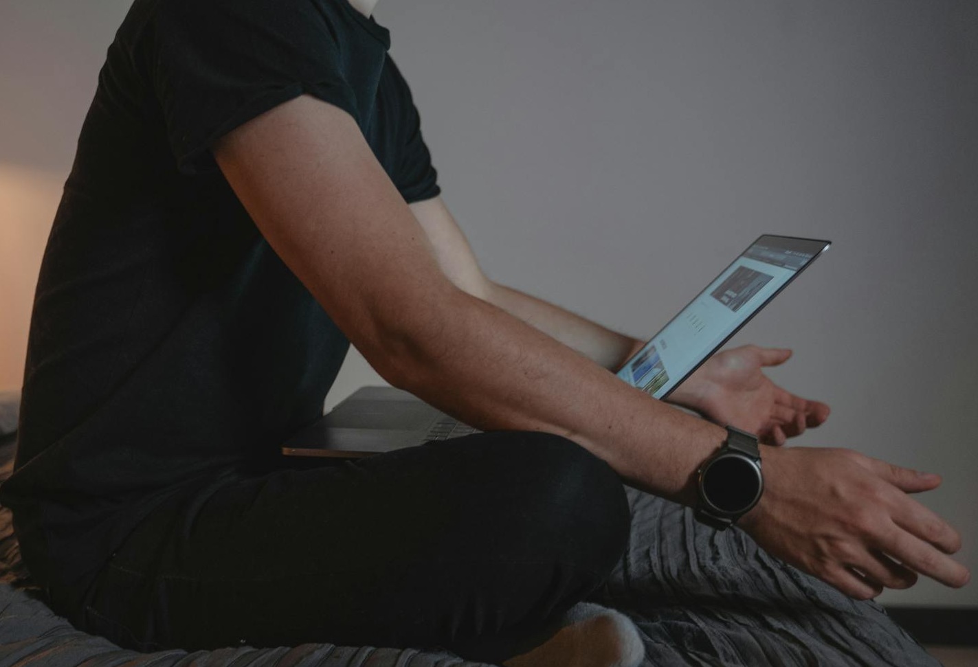 Man in Black T-shirt Sitting on Bed with laptop.