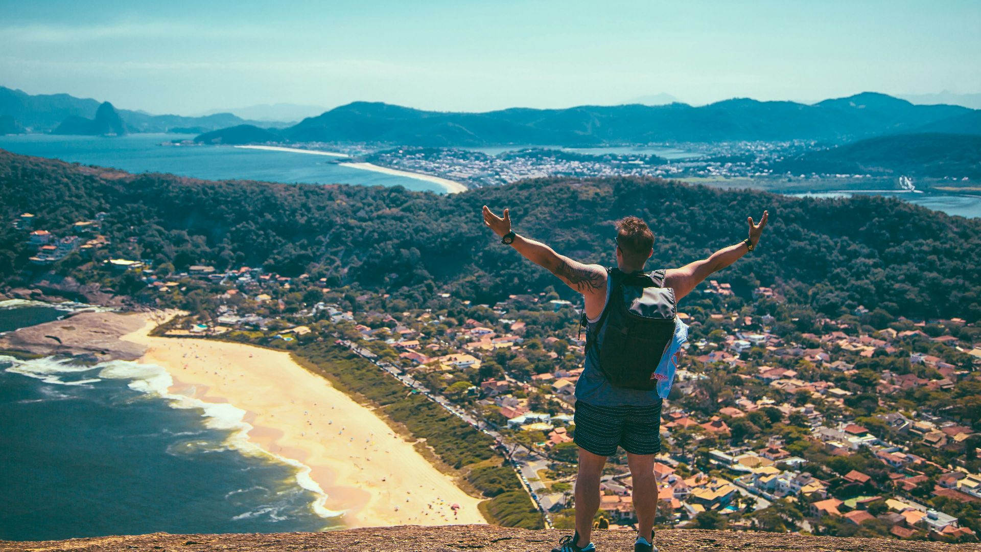 man standing front of seashore and houses