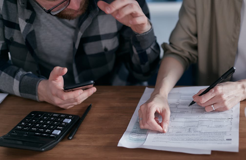 A man holding phone and a woman holding a pen