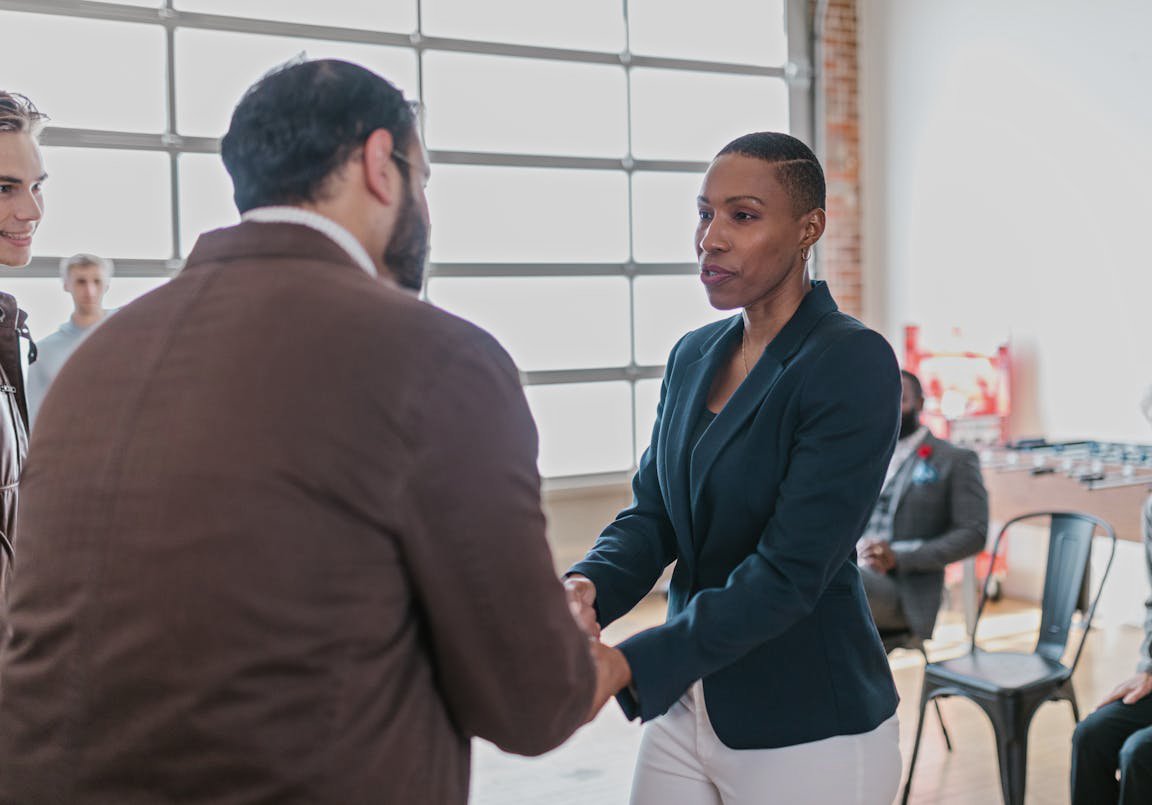 Woman in Black Blazer Shaking Hands with Man in Brown Blazer