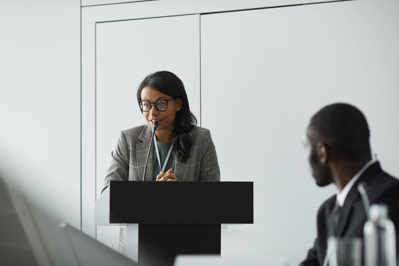 Woman Wearing Eyeglasses Talking Behind a Podium