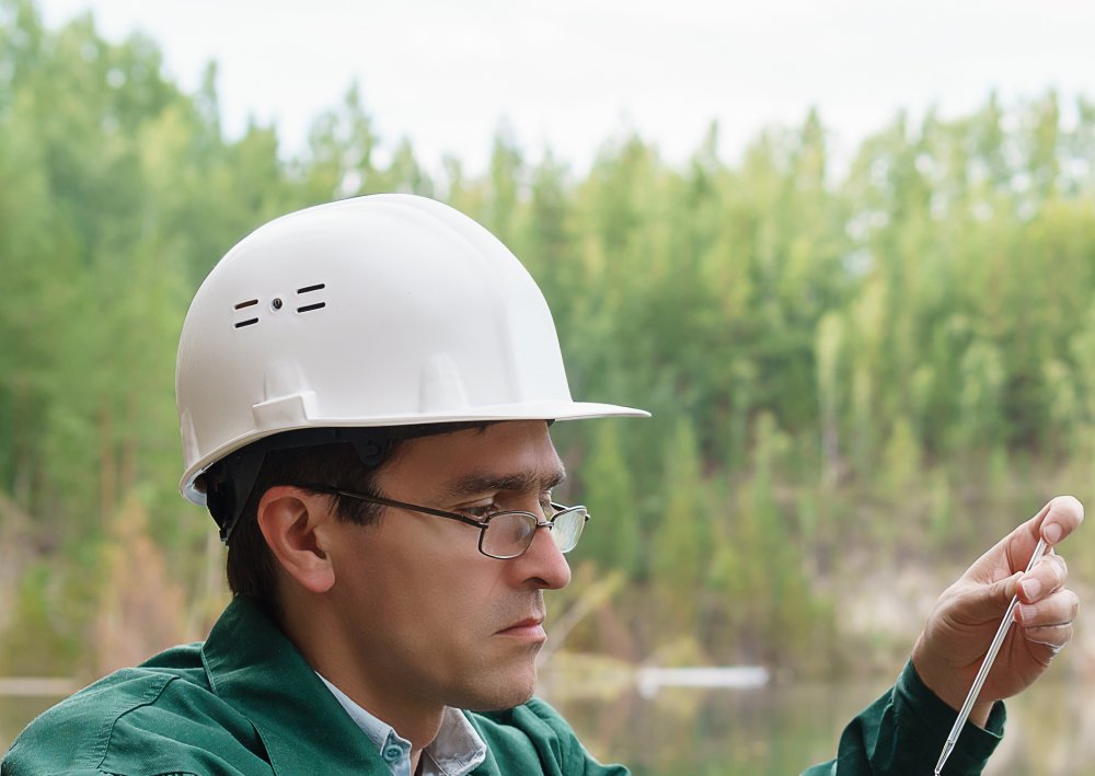 Hydrologist takes a sample of water from lake at the site of a flooded quarry