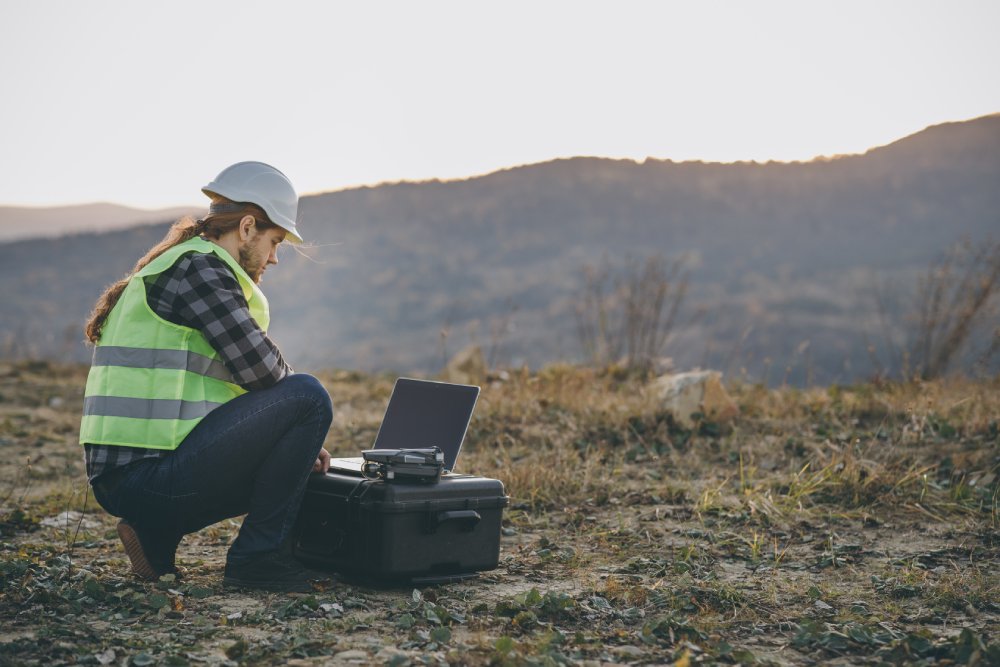 The engineer in the helmet works at the factory with an laptop