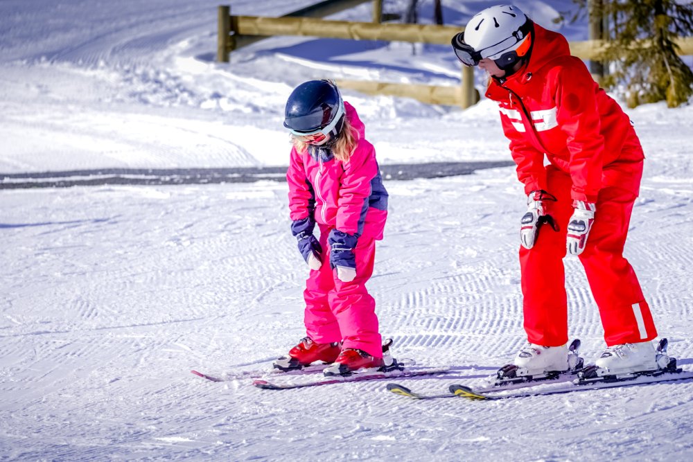 Portrait Photo of Professional ski instructor is teaching a child to ski