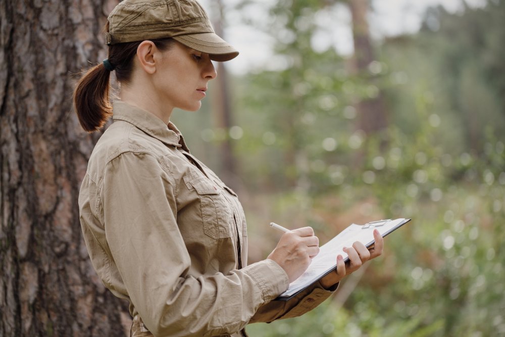 A woman forester in uniform with a clipboard monitoring national park