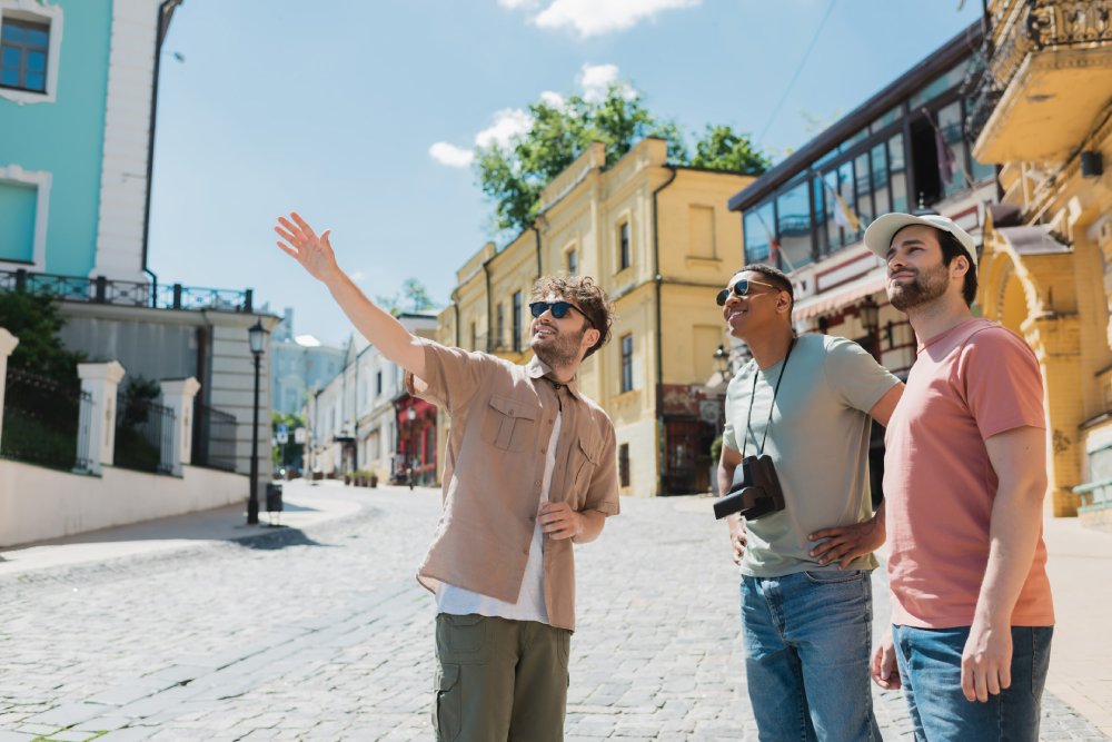 Tour guide in sunglasses pointing with hand during excursion with interracial tourists
