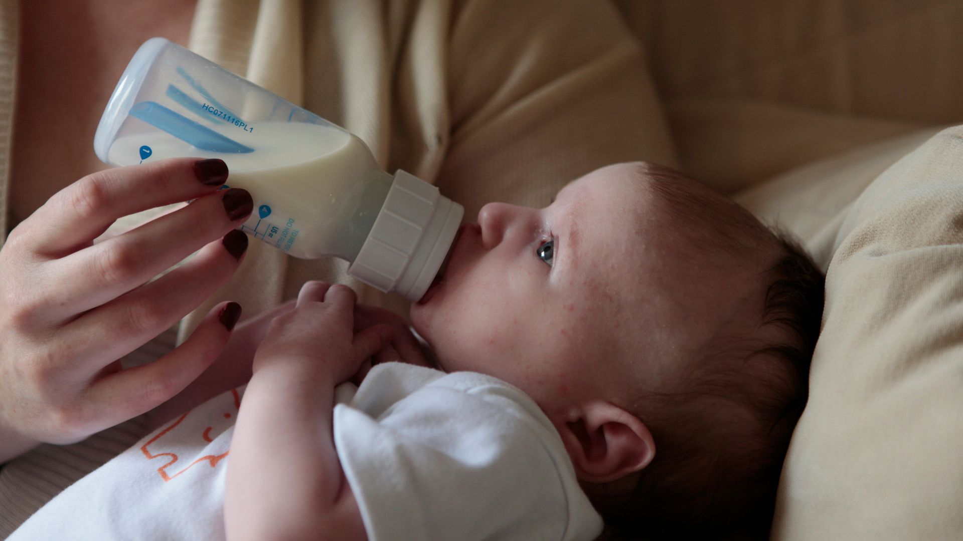 a woman feeding a baby with a bottle of milk