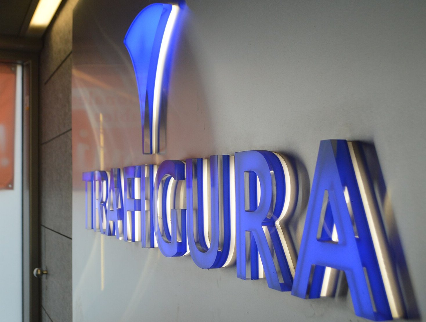 The image shows a three-dimensional, illuminated sign mounted on a light grey wall.