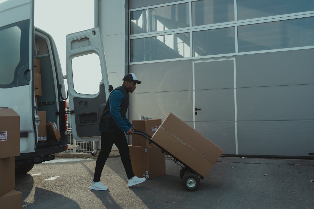 Delivery Man pushing a Trolley with Carton Boxes