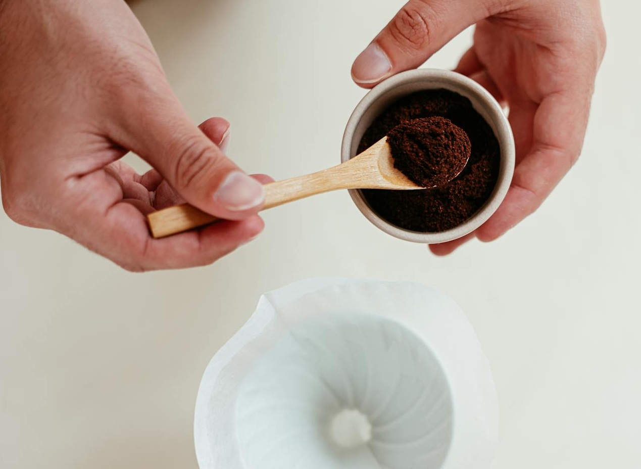 A Person Putting Ground Coffee on a Pour Over Set