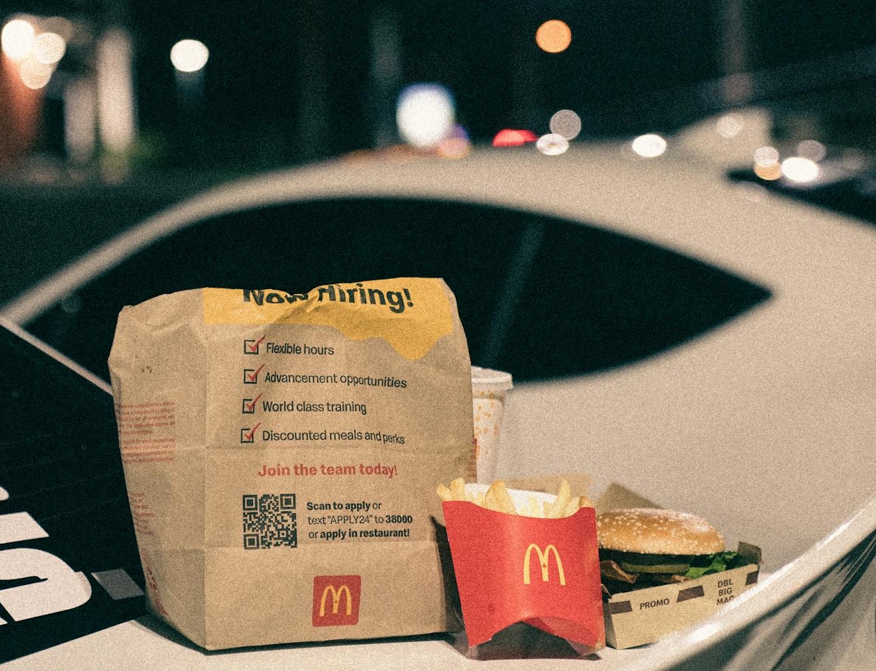 A mcdonald's bag is sitting on the hood of a car