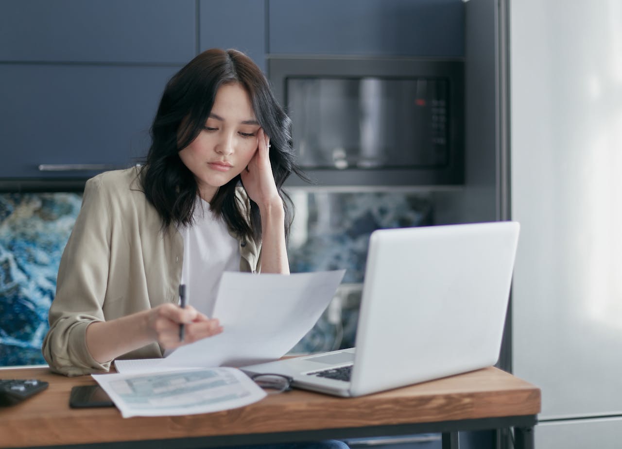 The image shows a woman with dark hair sitting at a table, seemingly engrossed in reviewing some documents
