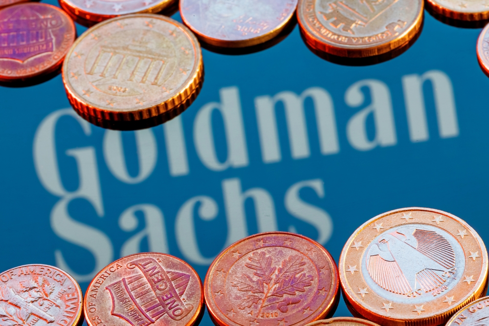 Variety of metal coins on background of Goldman Sachs bank logo