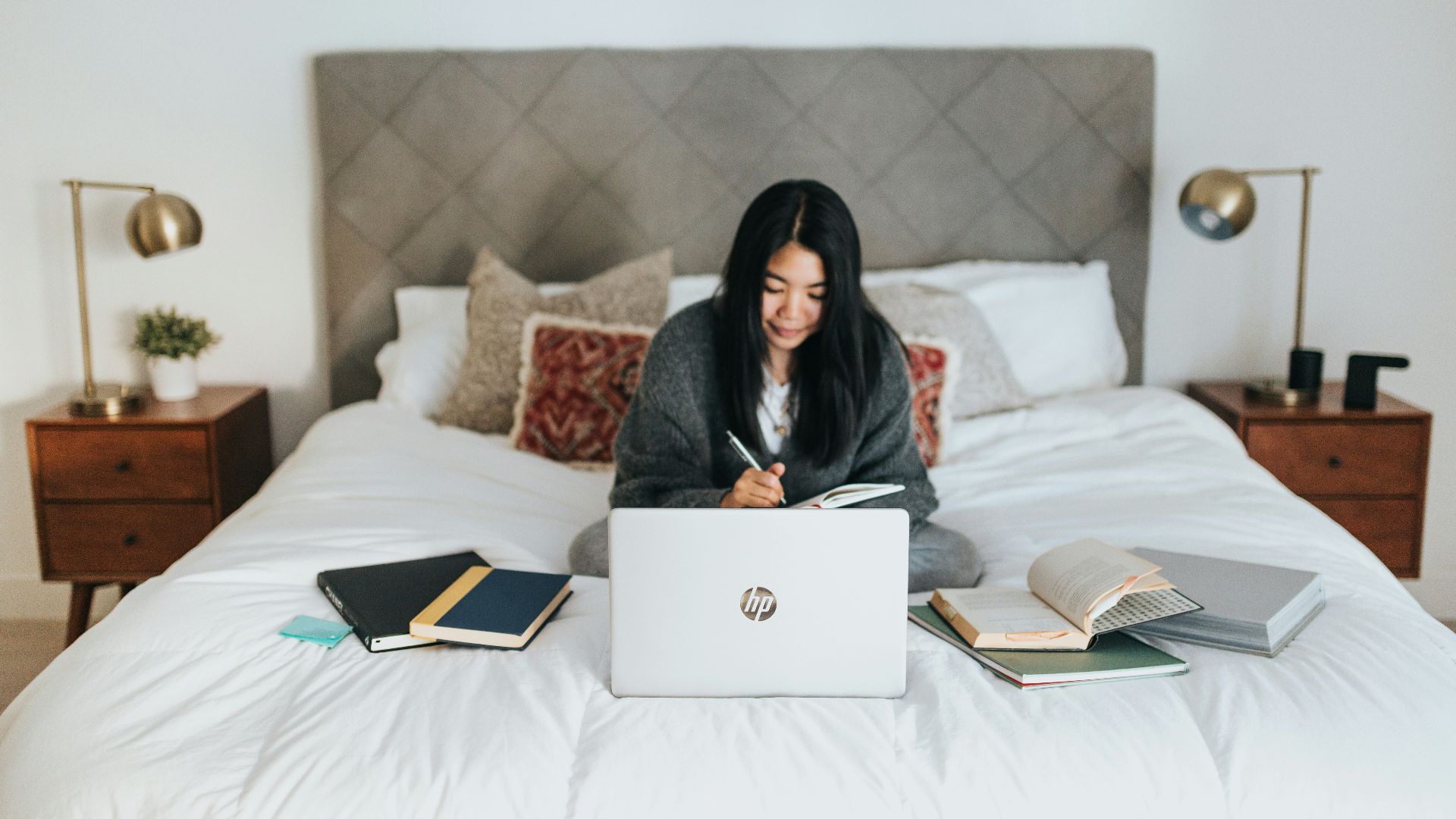 woman in black hijab sitting on bed using laptop