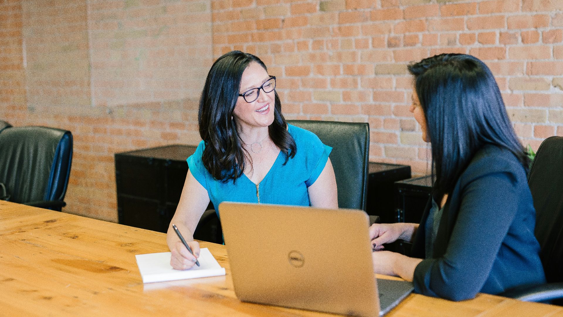 woman in teal t-shirt sitting beside woman in suit jacket