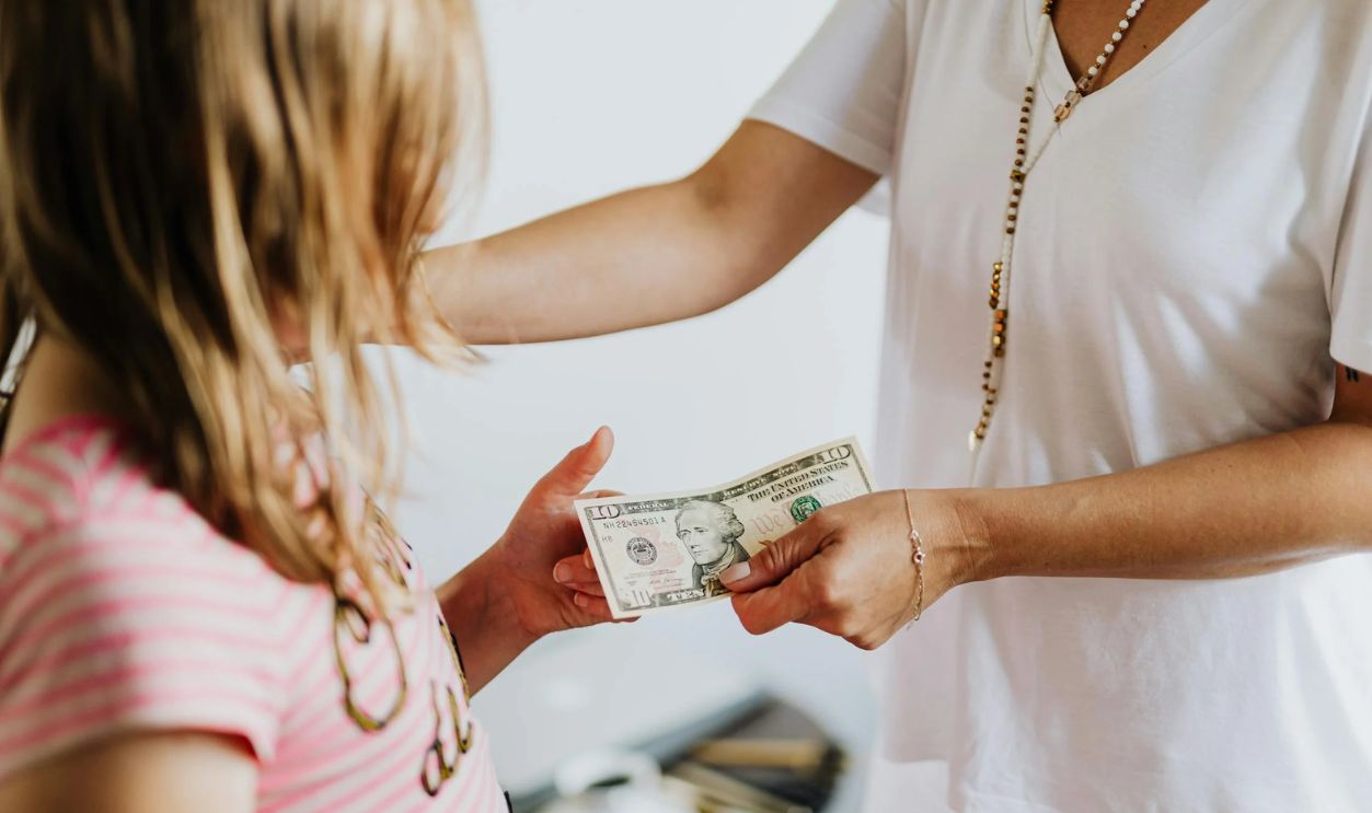 Woman Giving 10 Dollars to a Girl