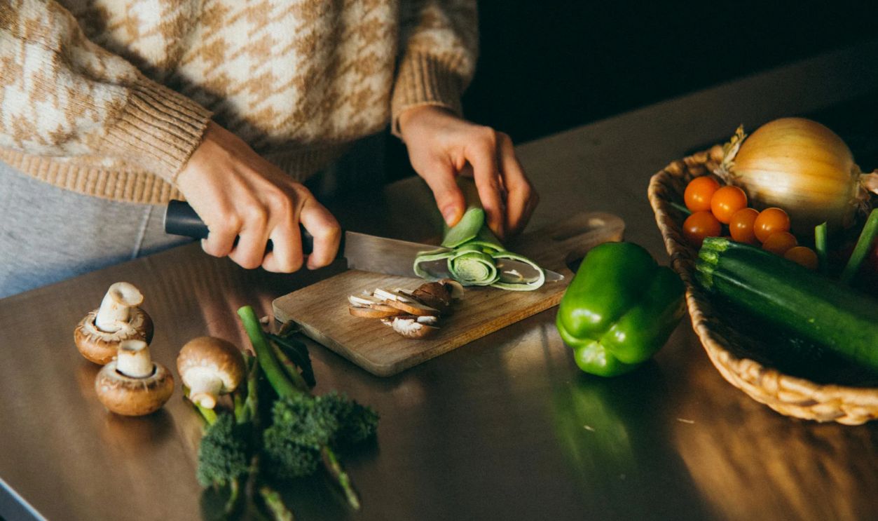 Person Slicing a Vegetable on Wooden Chopping Board