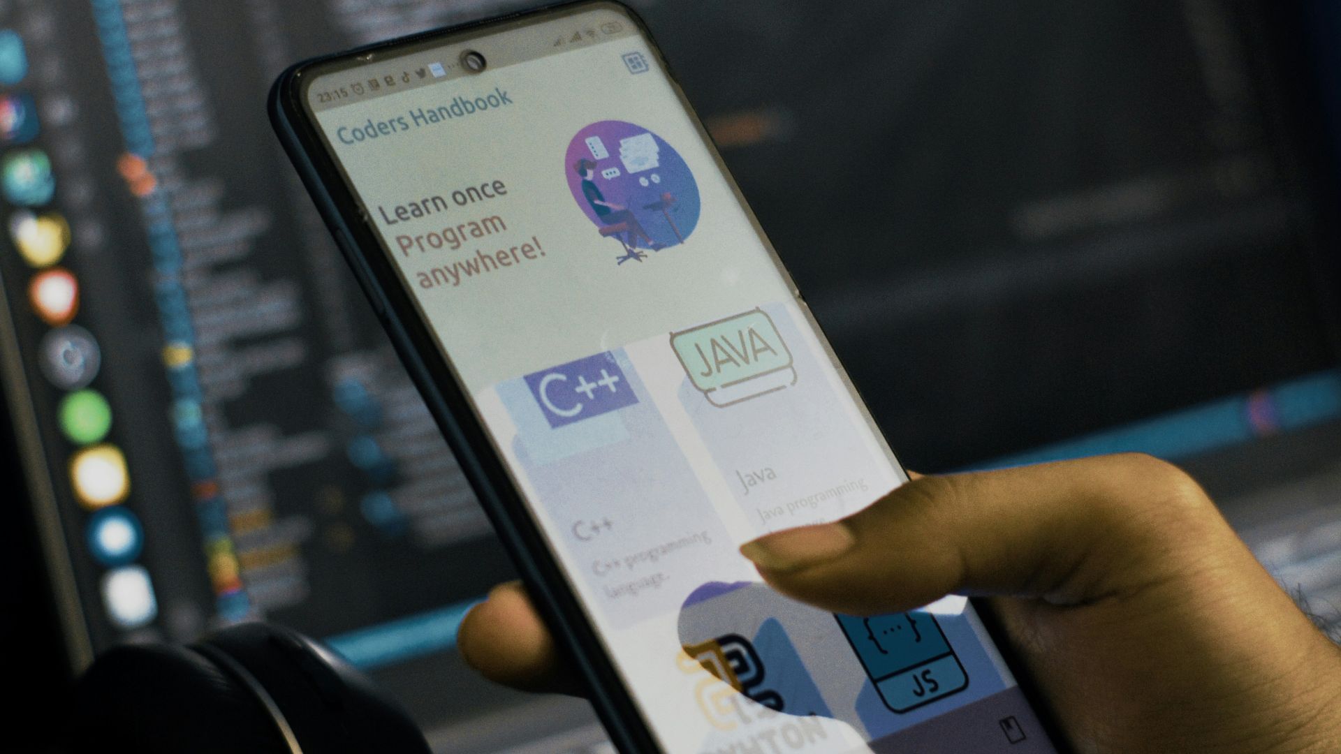 a person holding a cell phone in front of a laptop