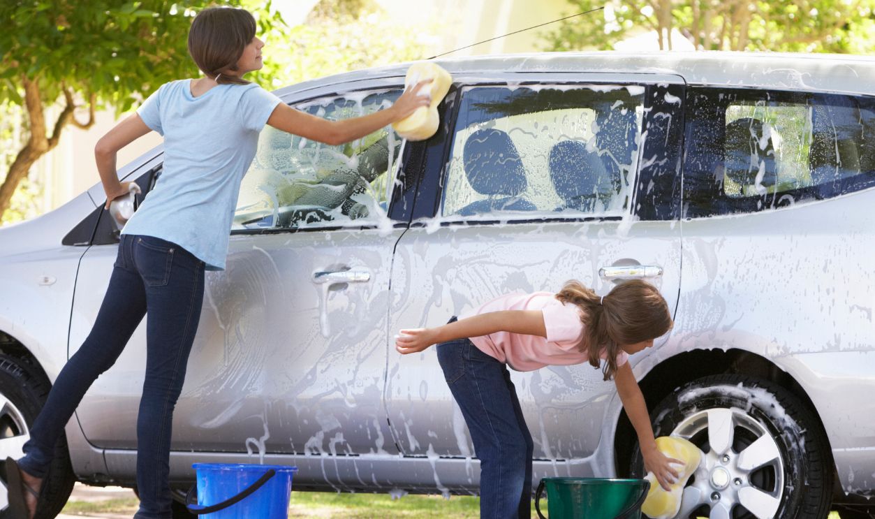 Two Girls Outside Washing Car Together.