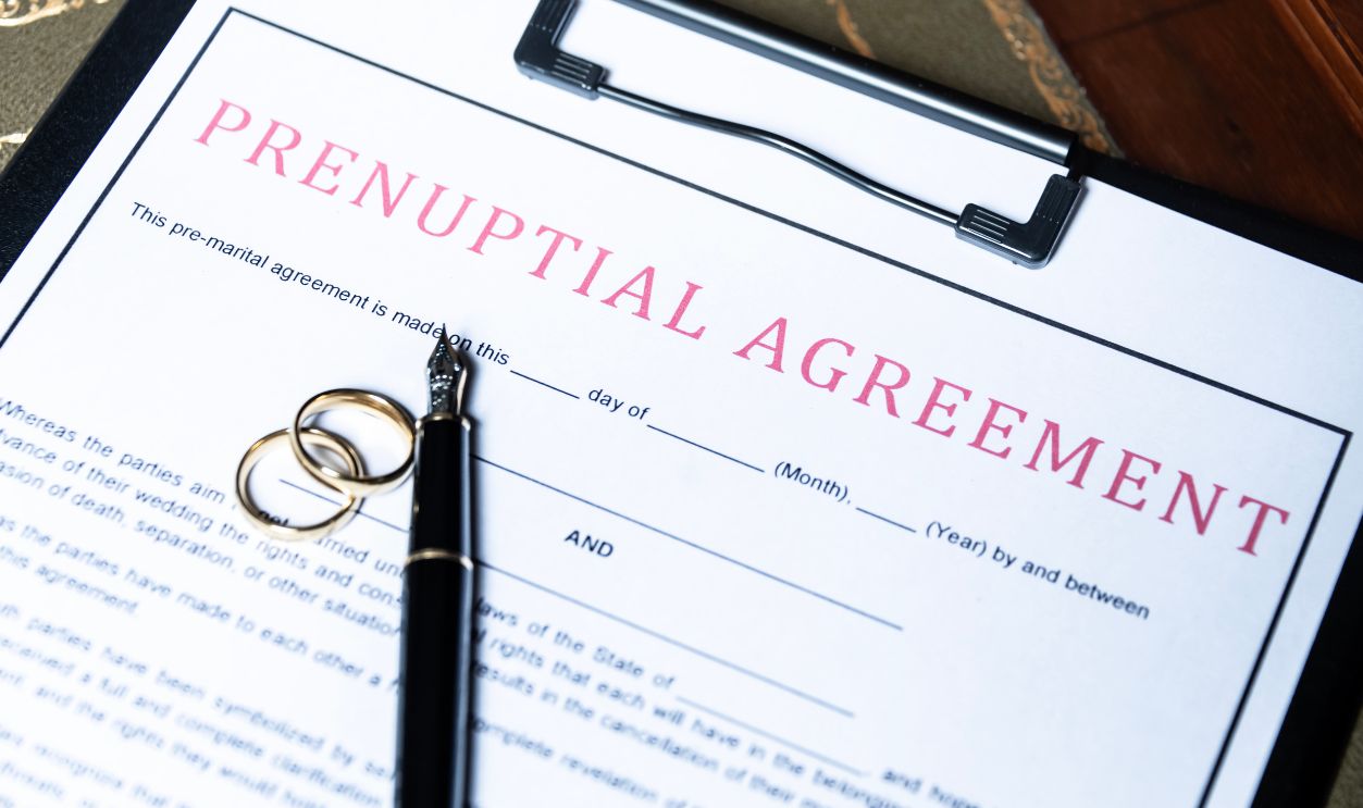 Close-up of a prenuptial agreement form with wedding rings and a fountain pen, indicating the legal aspects of marriage preparation
