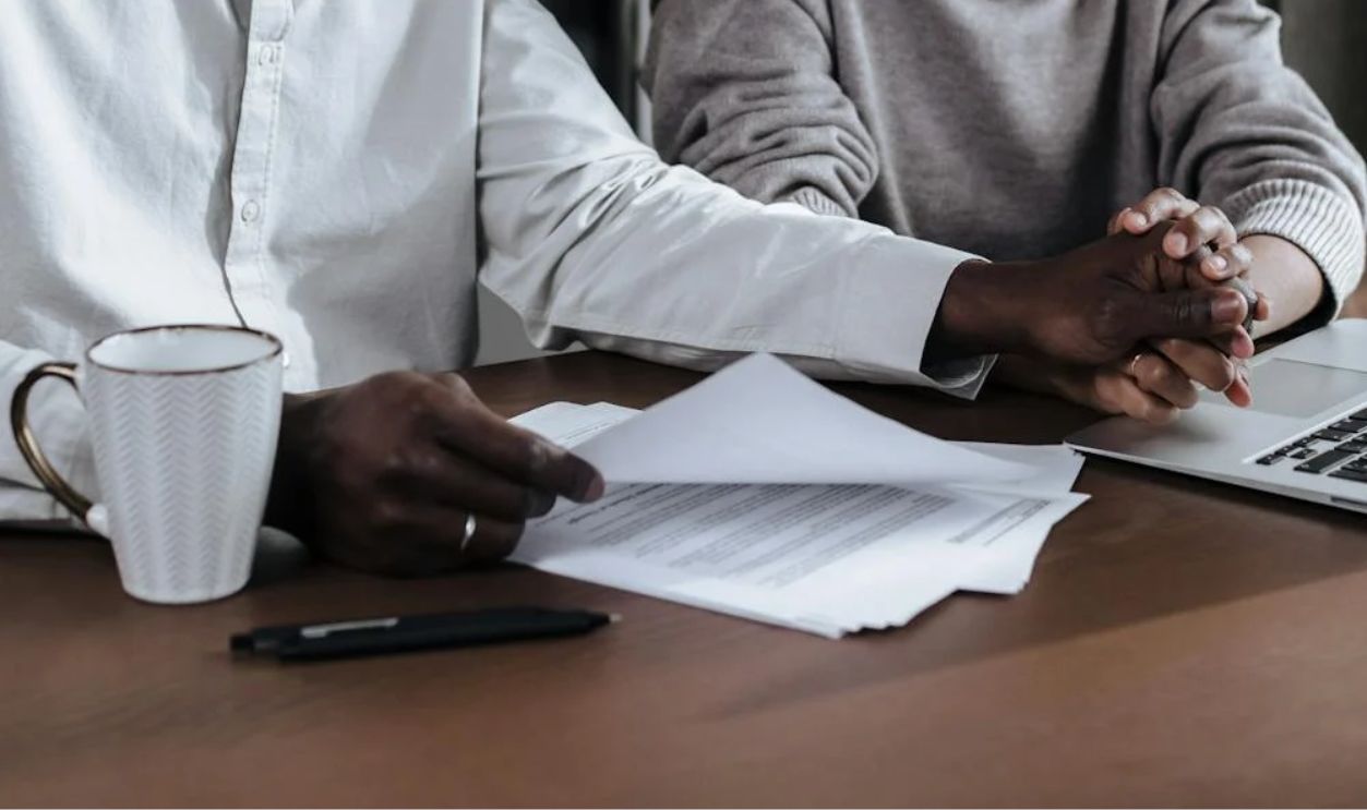 Couple Holding Hands While Reading Documents