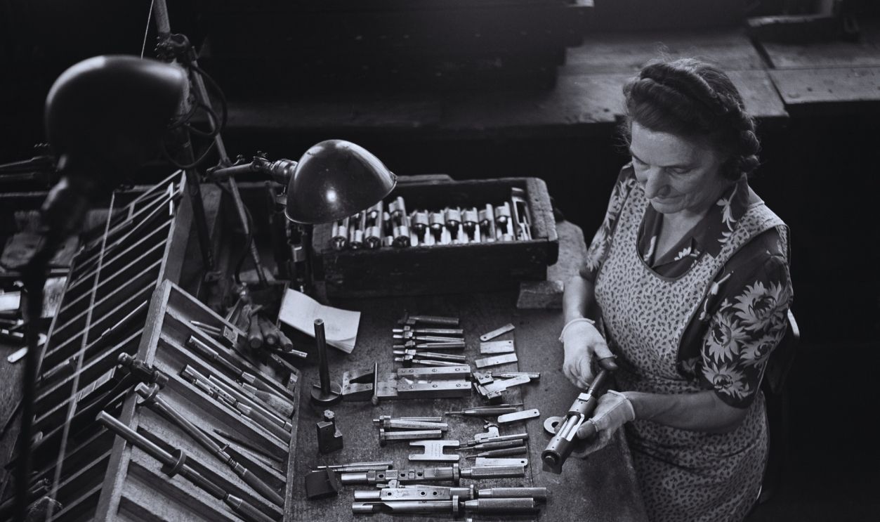 Gettyimages - 2025430505, Winchester Repeating Arms Company Factory, New Haven, Connecticut An employee sits with firing mechanism components on the workbench before her during the manufacture of Winchester rifles, at the Winchester Repeating Arms Company factory in New Haven, Connecticut, circa 1955.