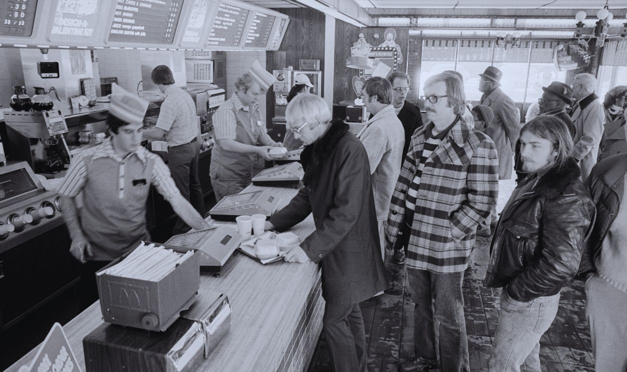 Gettyimages - 1318483525, In Line At McDonald's View along the counter of a McDonald's fast food restaurant as employees serve a line of customers, Washington DC, February 9, 1979.