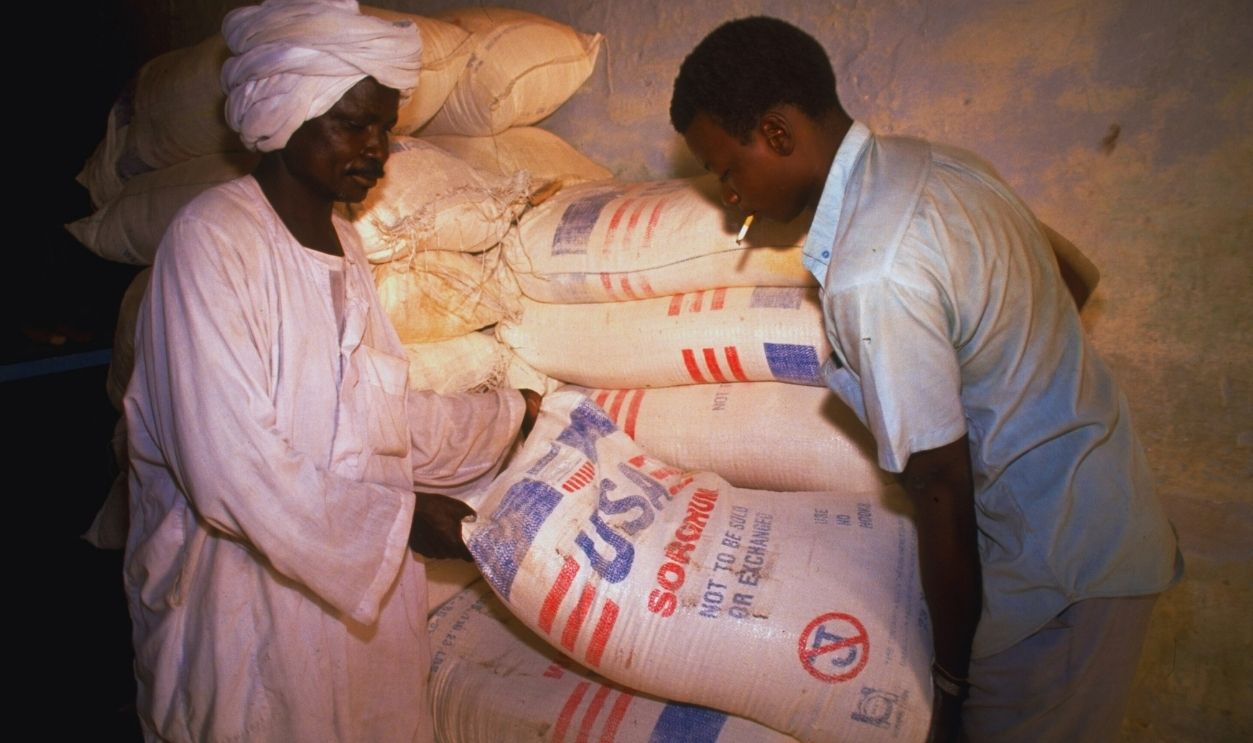 Gettyimages - 50595416, Bakery employees hefting sack labeled US Bakery employees hefting sack labeled USA Sorghum not to be exchanged or sold fr. pile